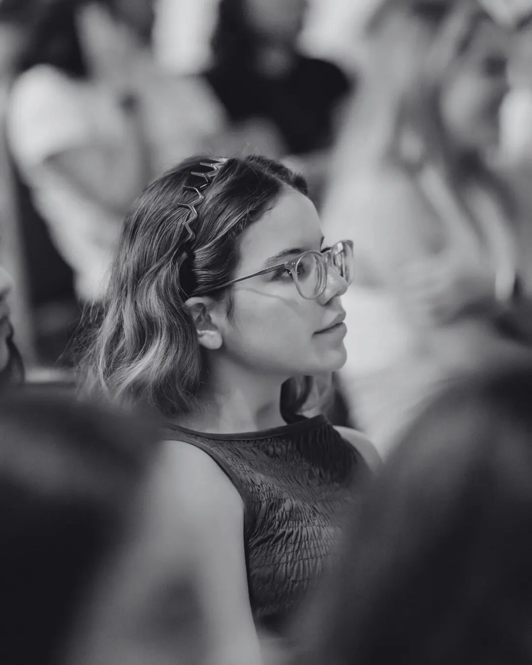 Retrato en blanco y negro de una asistente con lentes, atenta a la charla