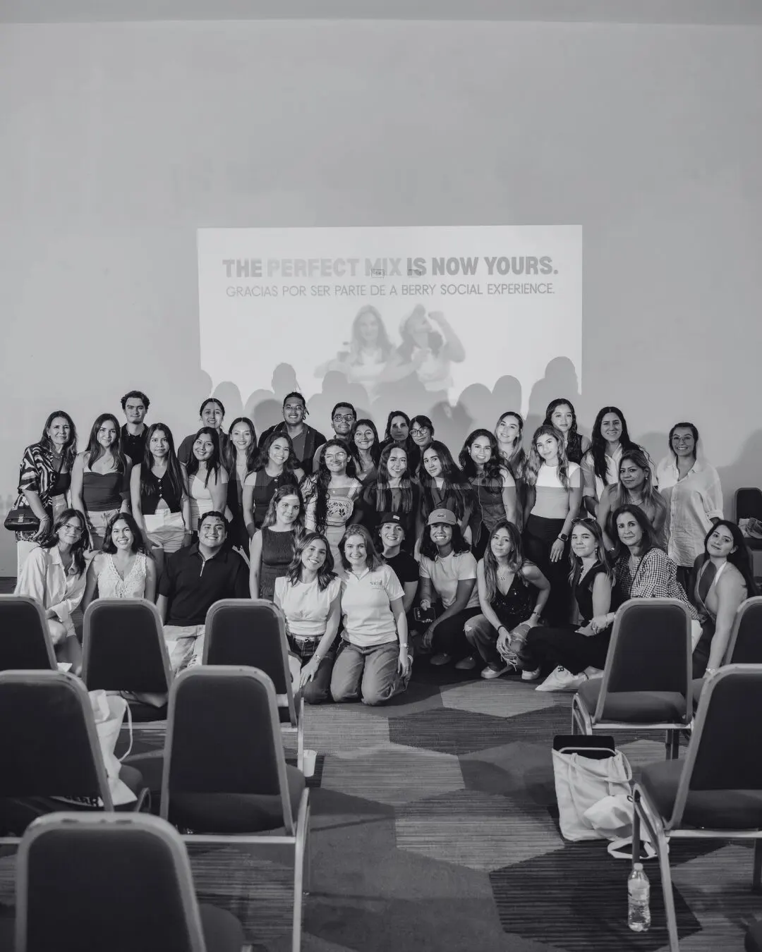 Foto grupal en blanco y negro de las asistentes frente a la pantalla "The perfect mix is now yours"