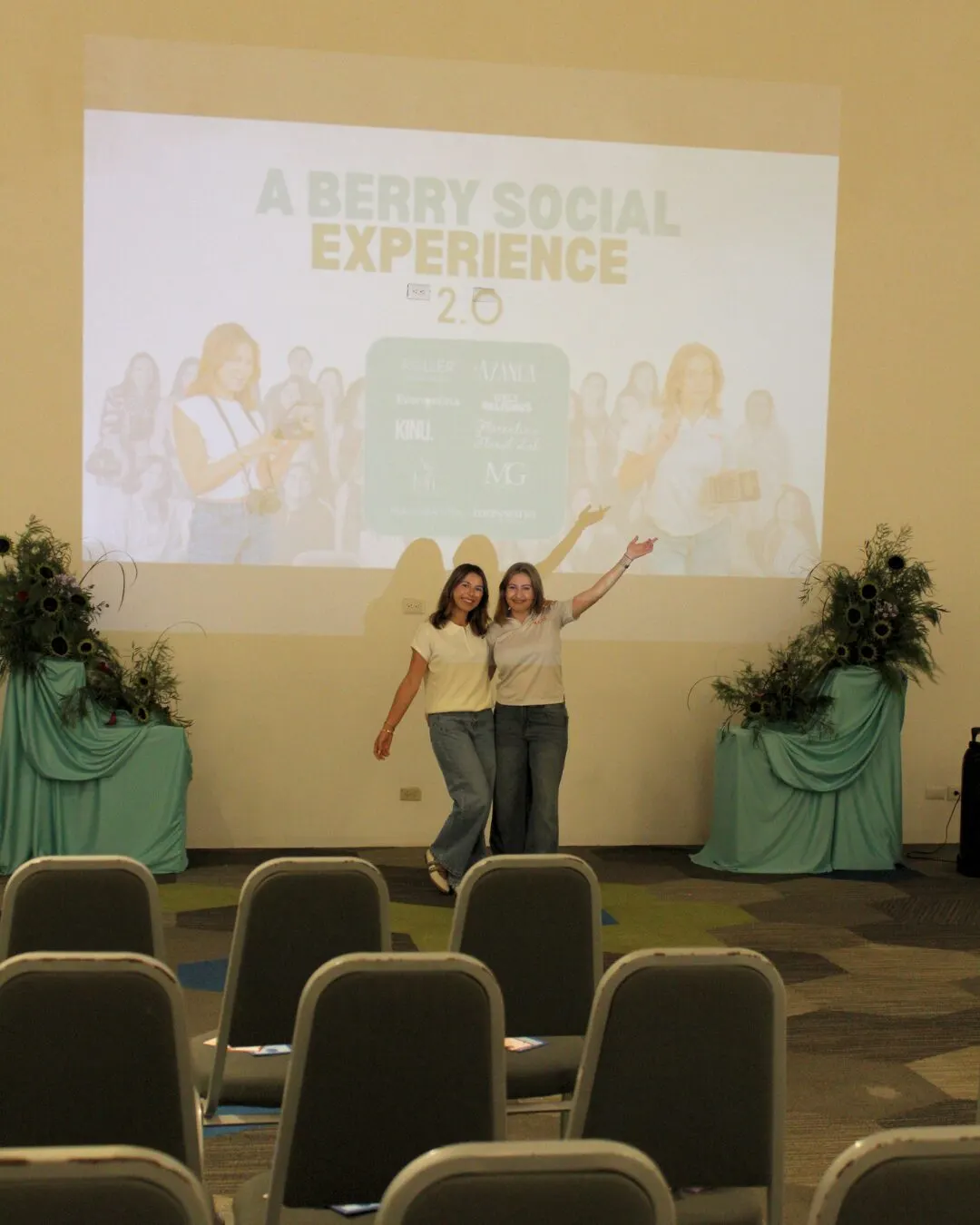 Las dos anfitrionas con los brazos en alto frente a la pantalla de A Berry Social Experience 2.0