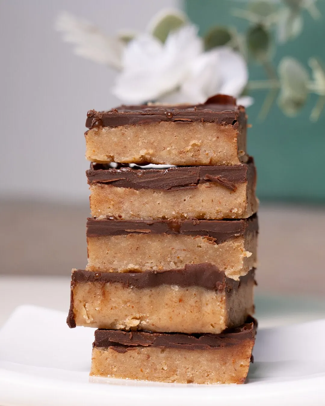 A stack of five chocolate-topped bars on a white plate.