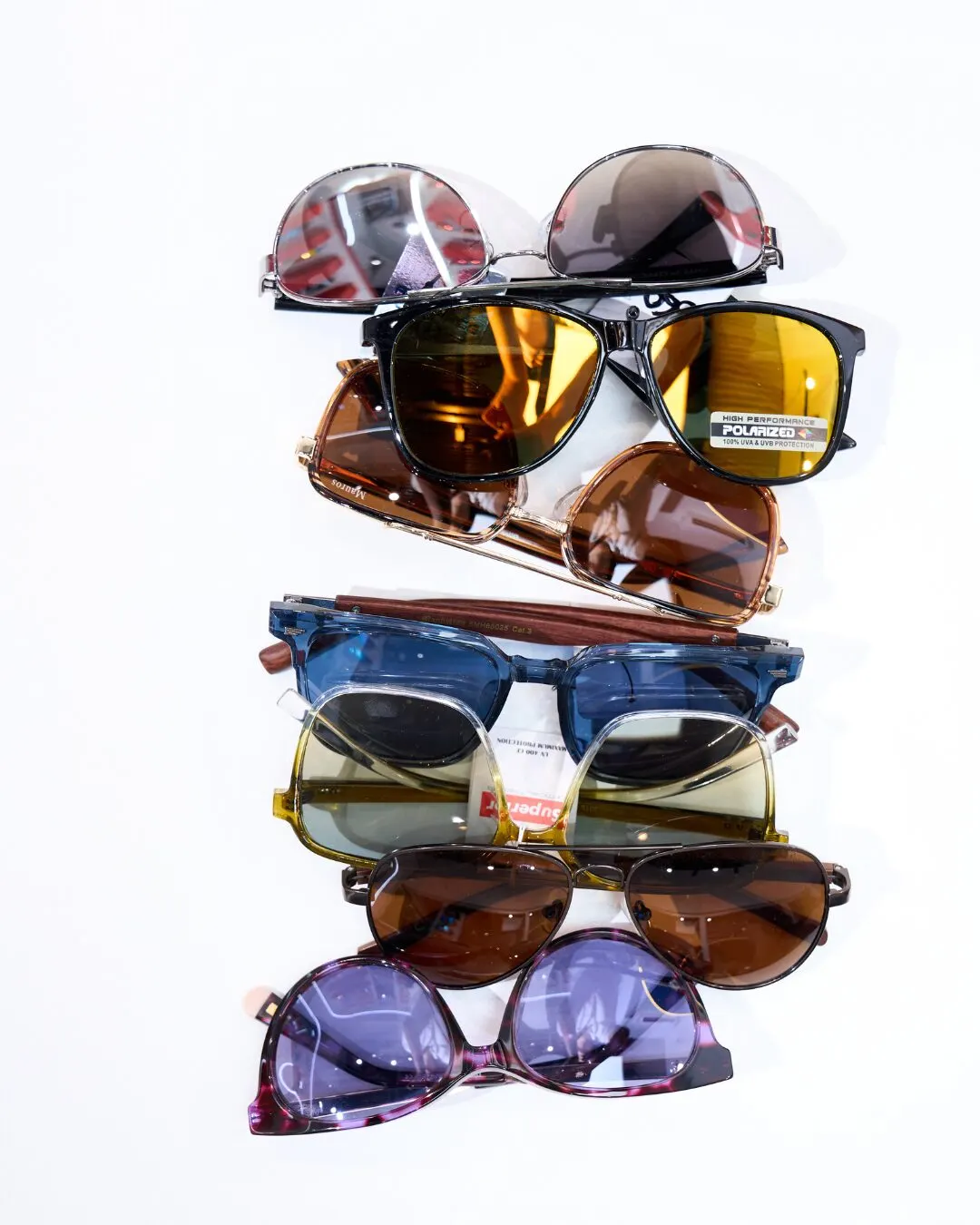 Several pairs of sunglasses with tinted lenses stacked on a white background.