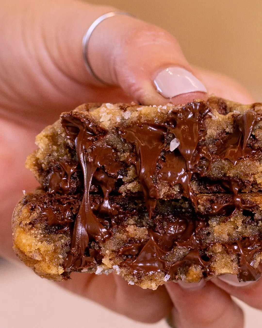 Mano partiendo una galleta rellena de chocolate derretido.