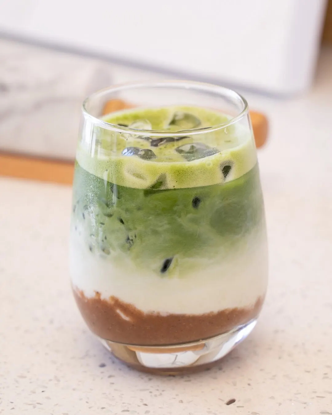 Matcha helado con leche en capas, en un vaso de vidrio.