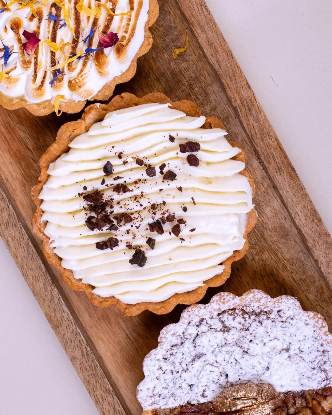Tartaletas de merengue y chocolate sobre una bandeja de madera.