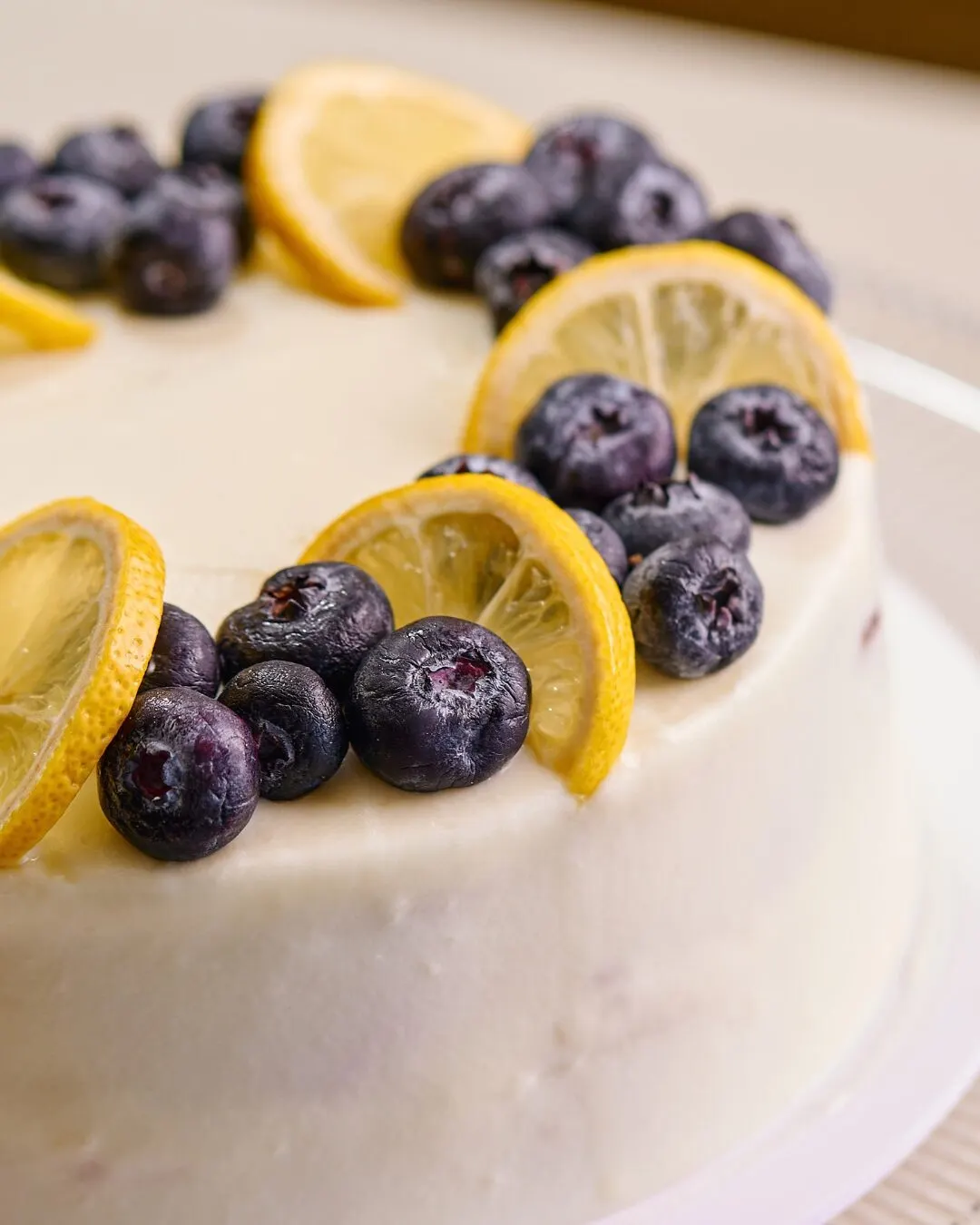 Pastel blanco decorado con arándanos y rodajas de limón.