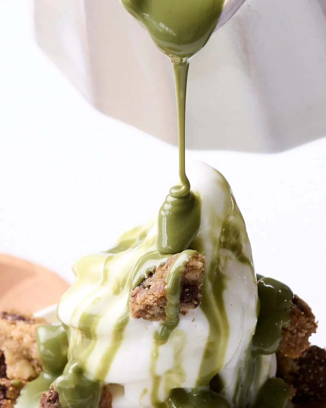 Matcha vertido sobre un helado suave con trozos de galleta.