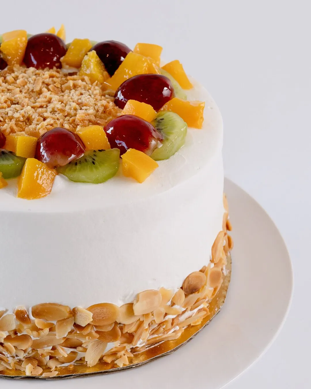 Pastel de frutas con almendras sobre un pedestal blanco.