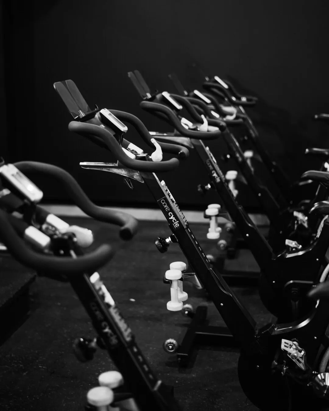 Fila de bicicletas de spinning del estudio, en blanco y negro.