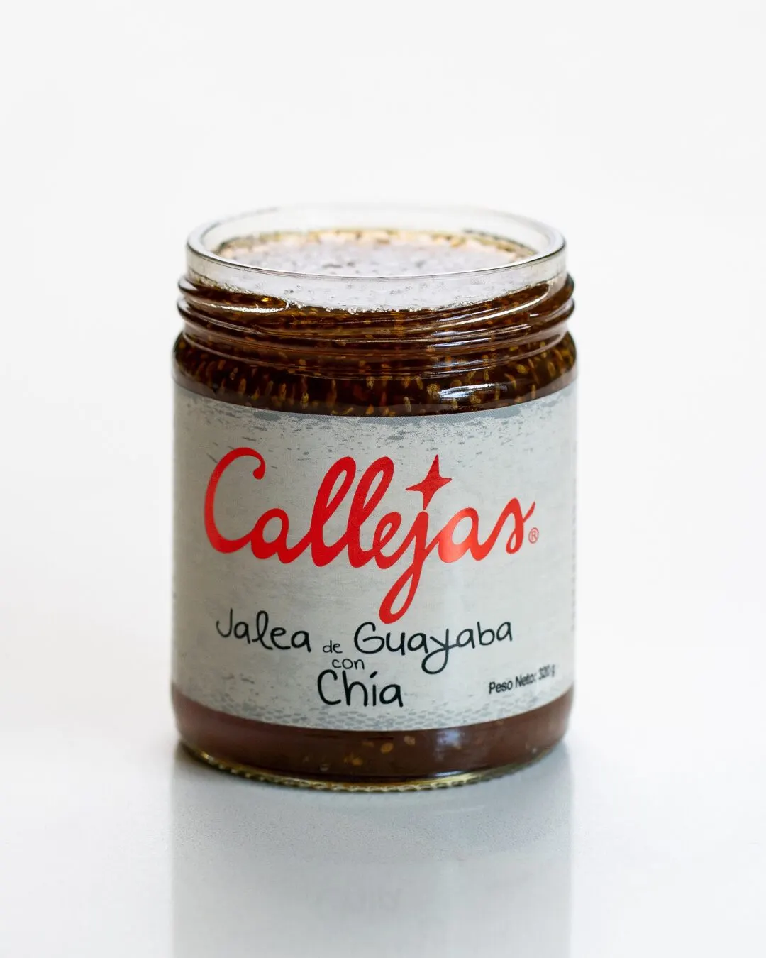 Frasco de jalea de guayaba con chía sobre un fondo blanco.