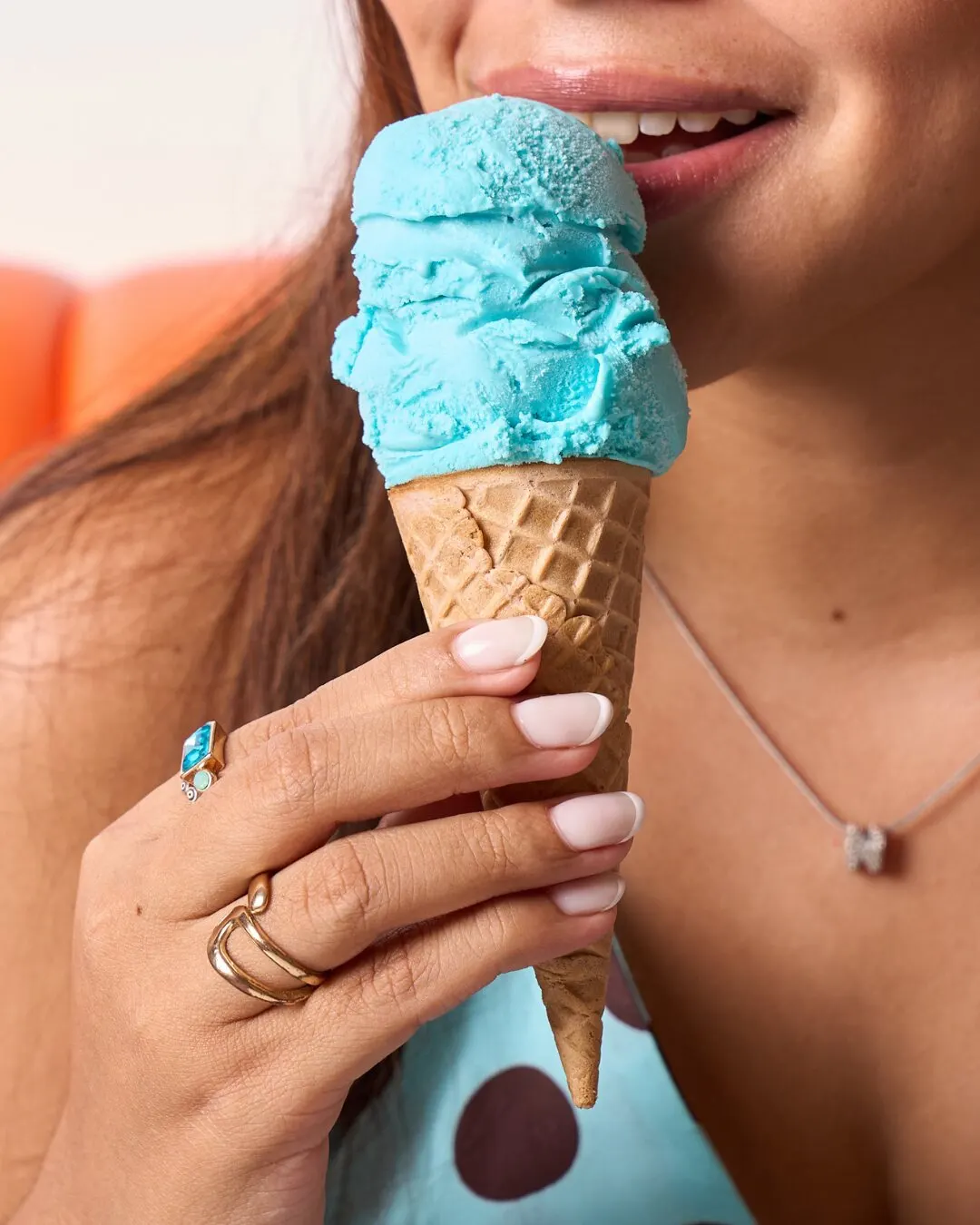 Mujer comiendo un cono de helado celeste.