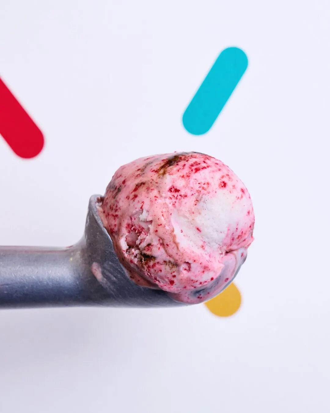 Cuchara de helado con una bola de helado de frutos rojos.